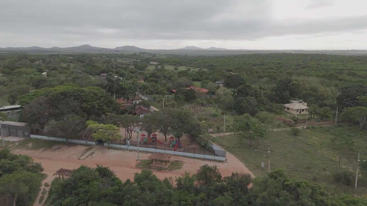 Pemandangan udara properti pedesaan berpagar dengan jalan tanah dan pedesaan hijau di baliknya.