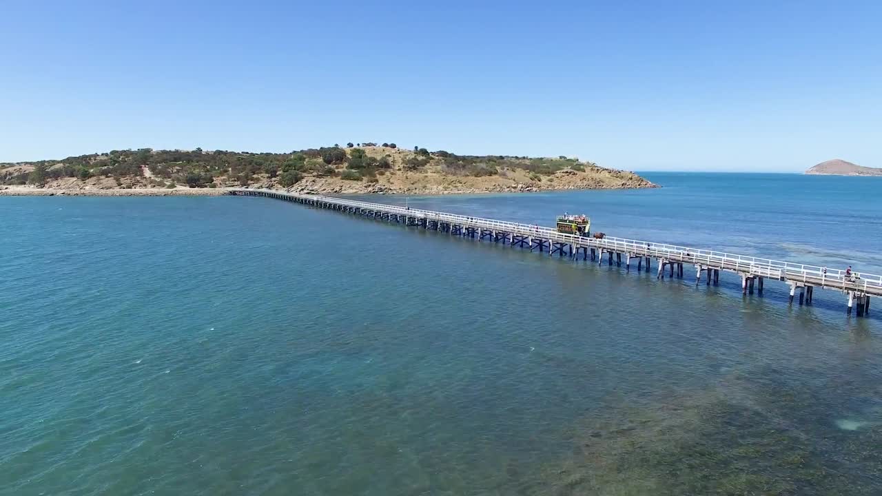 снимок с воздуха трамвая, запряженного лошадьми, пересекающего оригинальную дамбу гранитного острова через океан, южная австралия