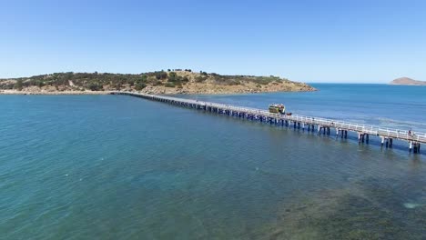 aerial shot of a horse-drawn tram crossing the original granite island causeway over the ocean, south australia