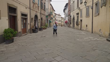 woman walking on typical street in the town of lucignano in arezzo, italy