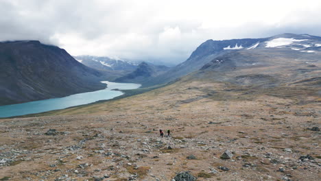 wide mountain valley landscape with people walking the big outdoors, panoramic aerial movement