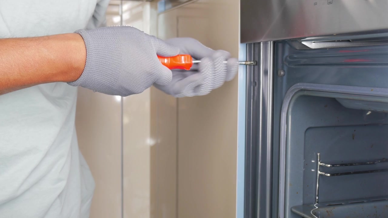 Tecnico che usa un cacciavite per riparare un forno da cucina