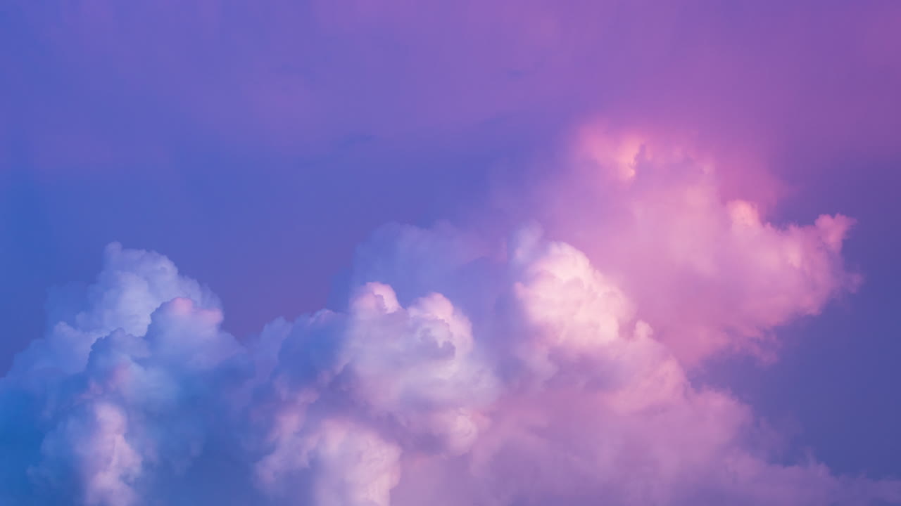 다채로운 파스텔 분홍색과 파란색의 폭풍우 구름이 저녁 해가 지는 동안 거품을 고 있습니다.