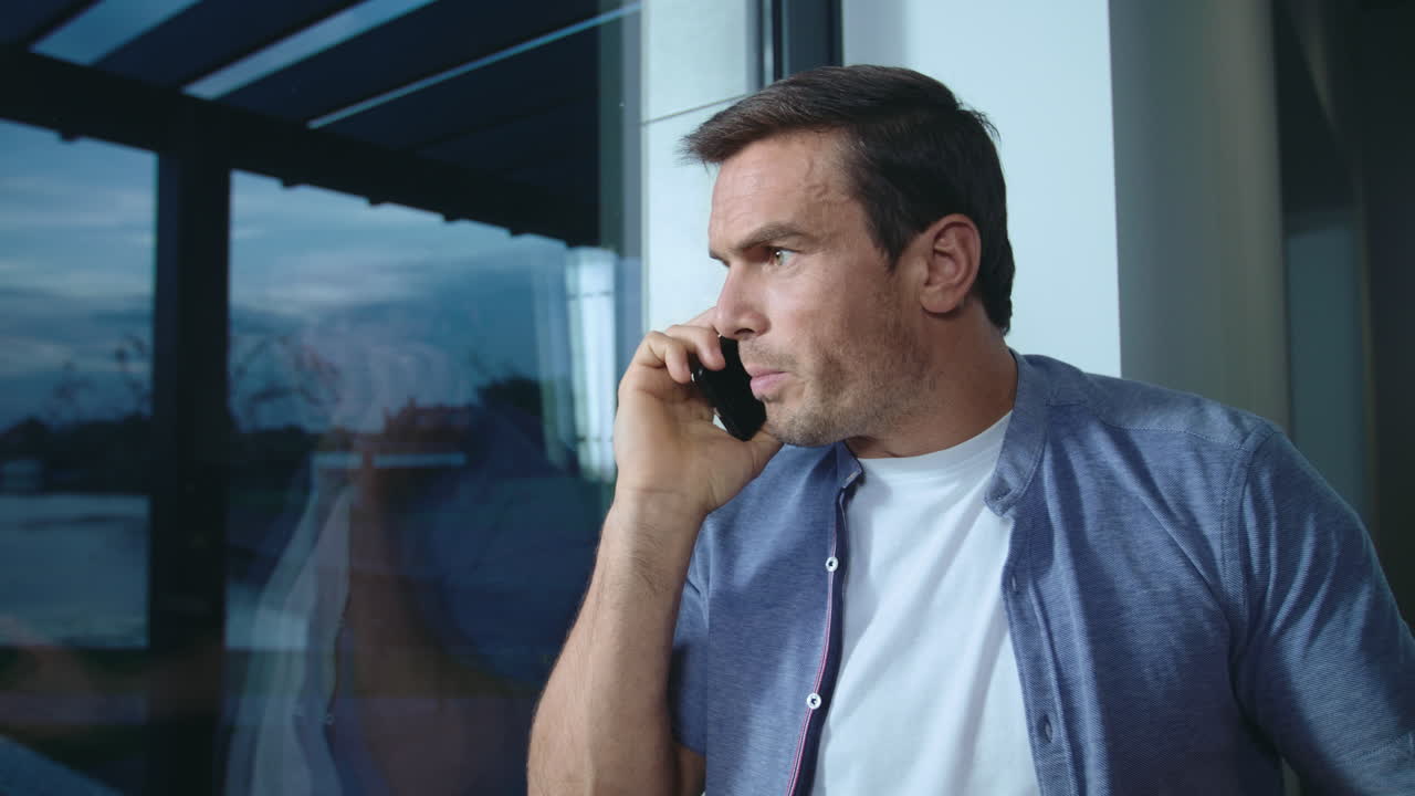 창문 근처에서 모바일로 이야기하는 사업가, 자신의 위치를 설명하는 긴장한 남자.
