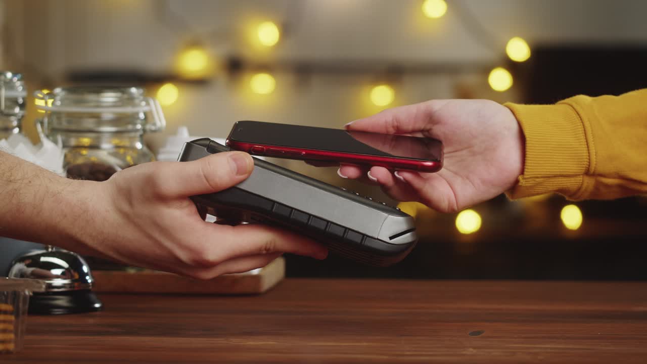 pagar con un primer plano de teléfono inteligente, utilizando la tecnología nfc en un restaurante. el cliente paga por teléfono móvil, tecnología sin contacto, pago sin contacto en un café.