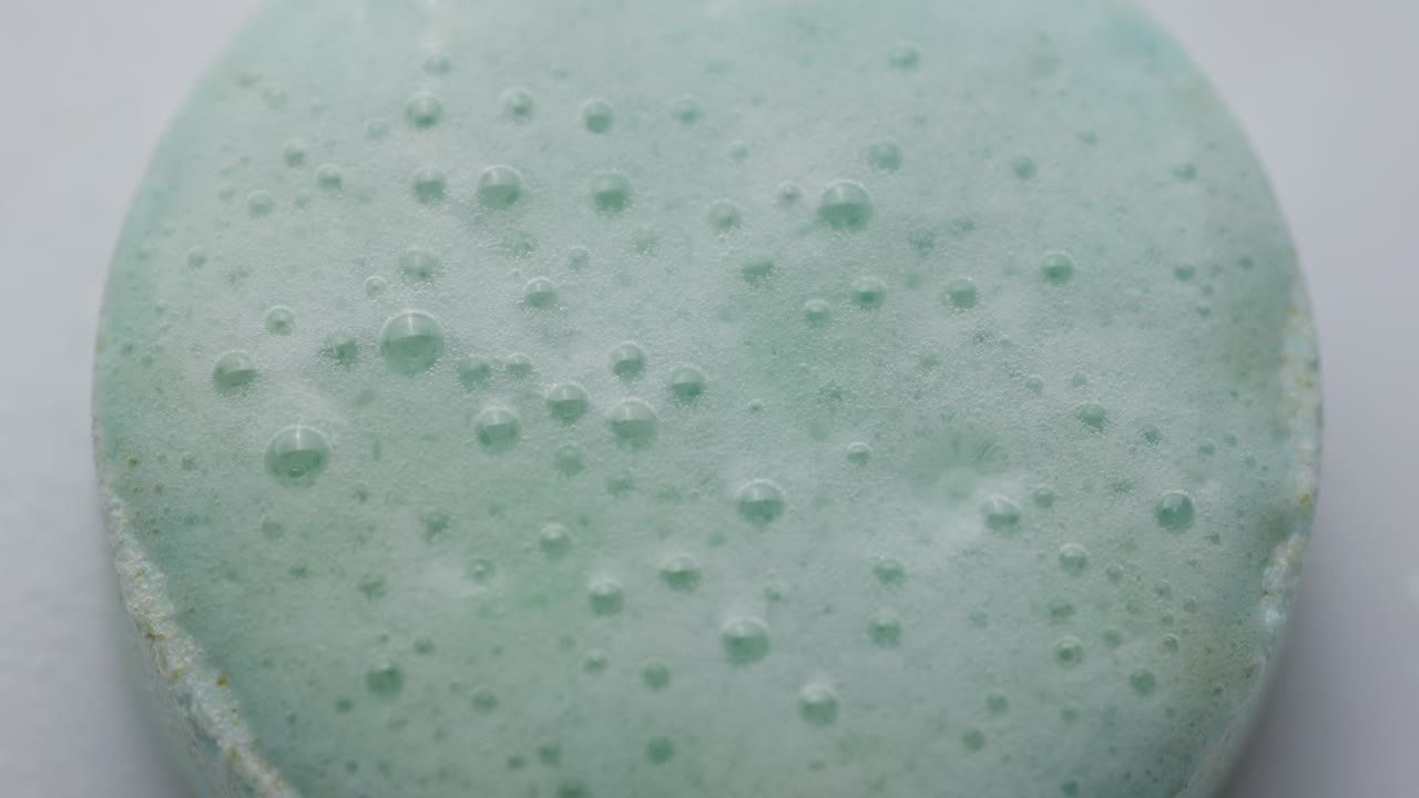 Effervescent tablet reacting in water, forming bubbles on the surface, macro view