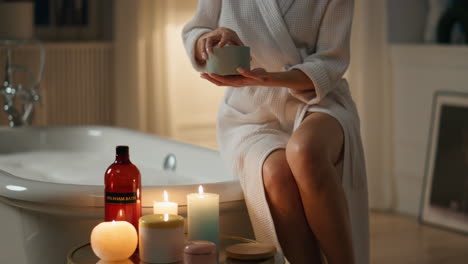 Smiling-lady-salting-bathtub-water-candles-room.-Closeup-woman-pouring-sea-salt