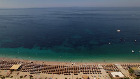 Blauer-Seehorizont-Und-Türkisfarbene-Lagune-Nahe-Paradiesstrand-Mit-Sonnenschirmen,-Urlaubsort-In-Albanien