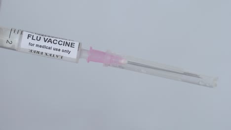 medical man removing the needle from injection filled with flu vaccine, close up shot