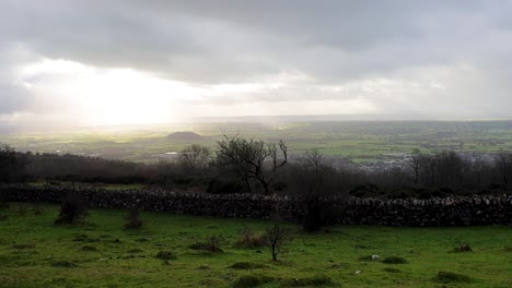 Old-dry-stone-wall-and-rural-English-countryside-landscape-view-of-pasture-farmland-fields-including-Cheddar-Reservoir-in-Somerset,-West-Country-of-England