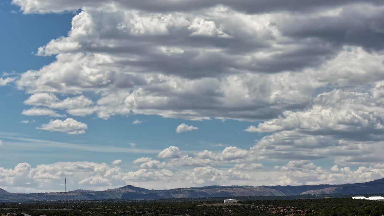 A cinematic drone timelapse captures dramatic clouds shifting over a rugged southwest landscape. The rapid atmospheric motion creates an epic and scenic background