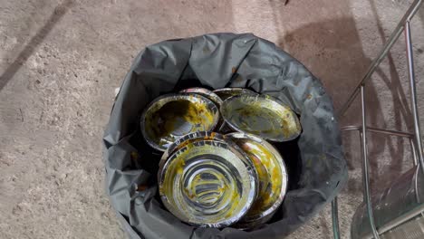 una toma en movimiento de un hombre tirando un plato de papel al basurero después de comer