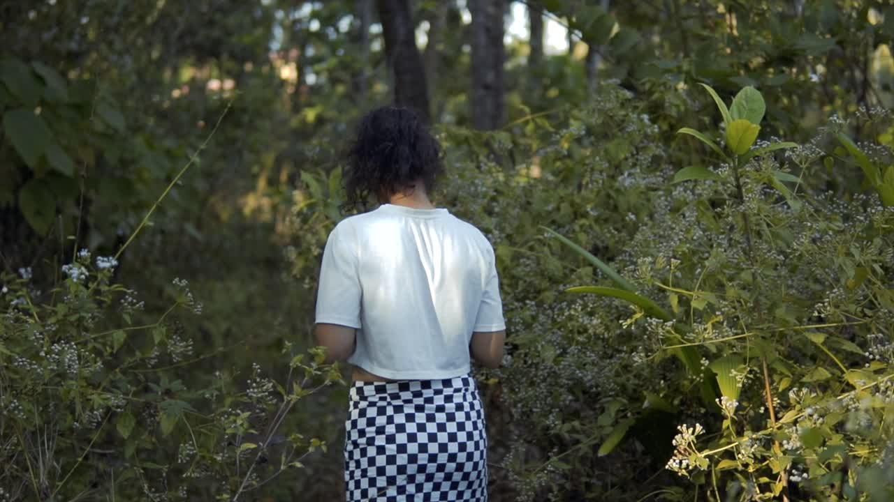 entre los árboles: una niña explorando la naturaleza con una flor