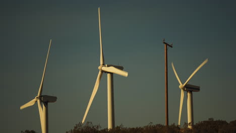 Ständige-Nahaufnahme-Von-Rotoren-Und-Flügeln-Von-3-Windkraftanlagen-In-Einem-Windpark-Während-Des-Sonnenuntergangs-In-Der-Nähe-Von-Palm-Springs-In-Der-Mojave-Wüste,-Kalifornien,-USA