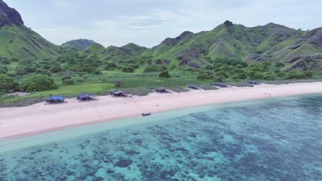 Drones-Rodeando-Un-Pueblo-Costero-En-Una-Isla-Con-Arena-Rosa-Rodeada-De-Arrecifes-De-Coral