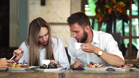 Multi-ethnic-group-of-young-friends-talking-and-using-smartphones-apps-on-wifi-in-cafe,-happy-millennial-people-having-fun-with-phones-sharing-coffee-house-table-enjoying-meeting-in-public-place