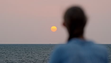 a serene moment in galle, sri lanka, as a woman gazes at the vast ocean during a breathtaking sunset.
