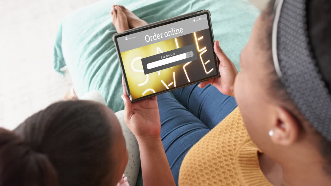 African american mother and daughter using tablet, shopping online during sale, slow motion