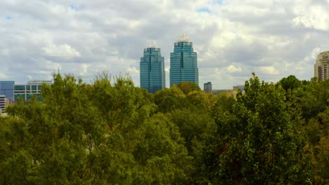 aerial shot slowly rising above the trees to reveal the king and queen towers in atlanta