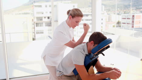 female therapist massaging man sitting on massage chair