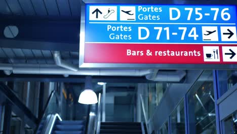 gates sign and and mechanical stairs at an airport