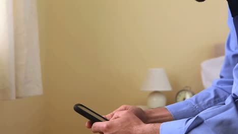 un hombre de negocios enviando mensajes de texto con su teléfono inteligente en la cama.