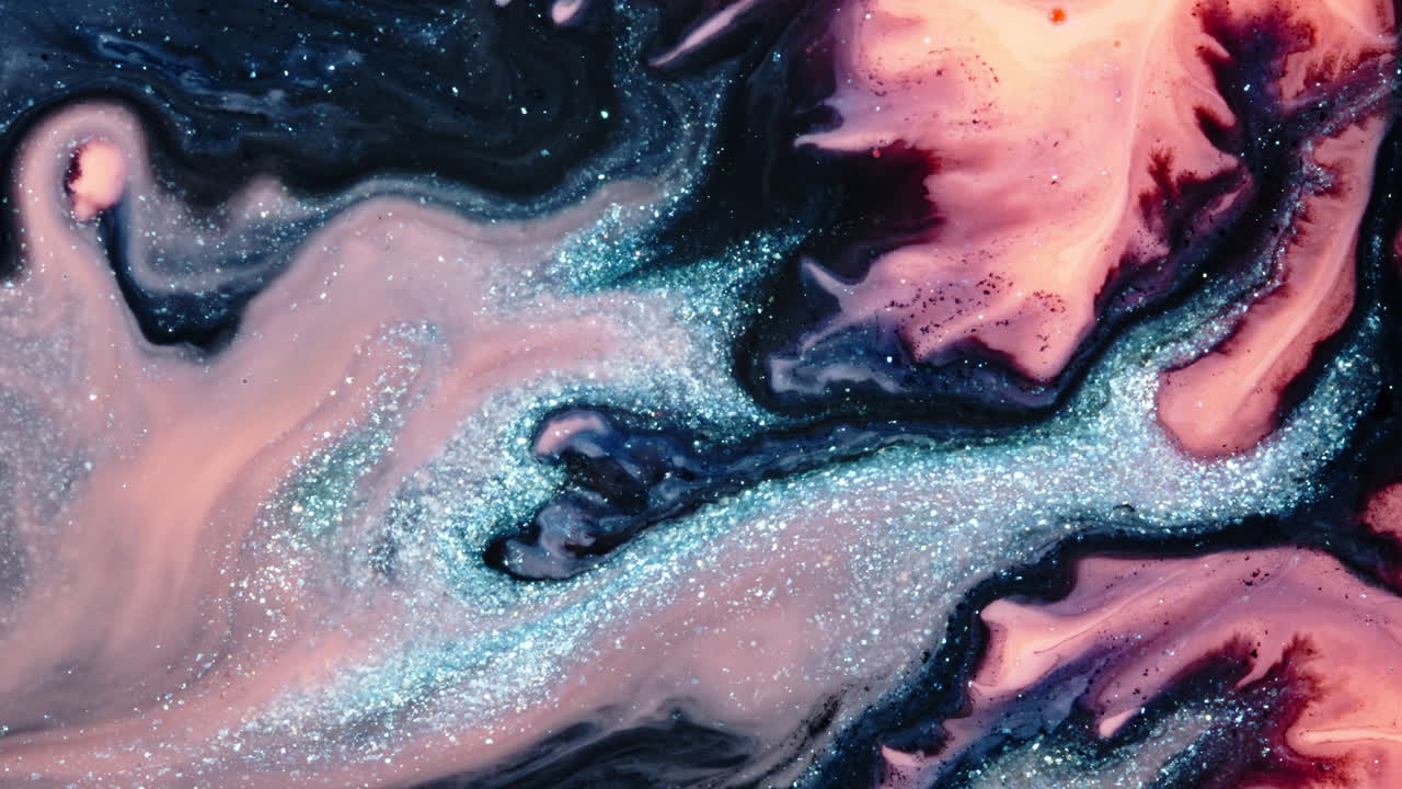 Swirling substances mixing with glittering blue and pink hues, macro shot