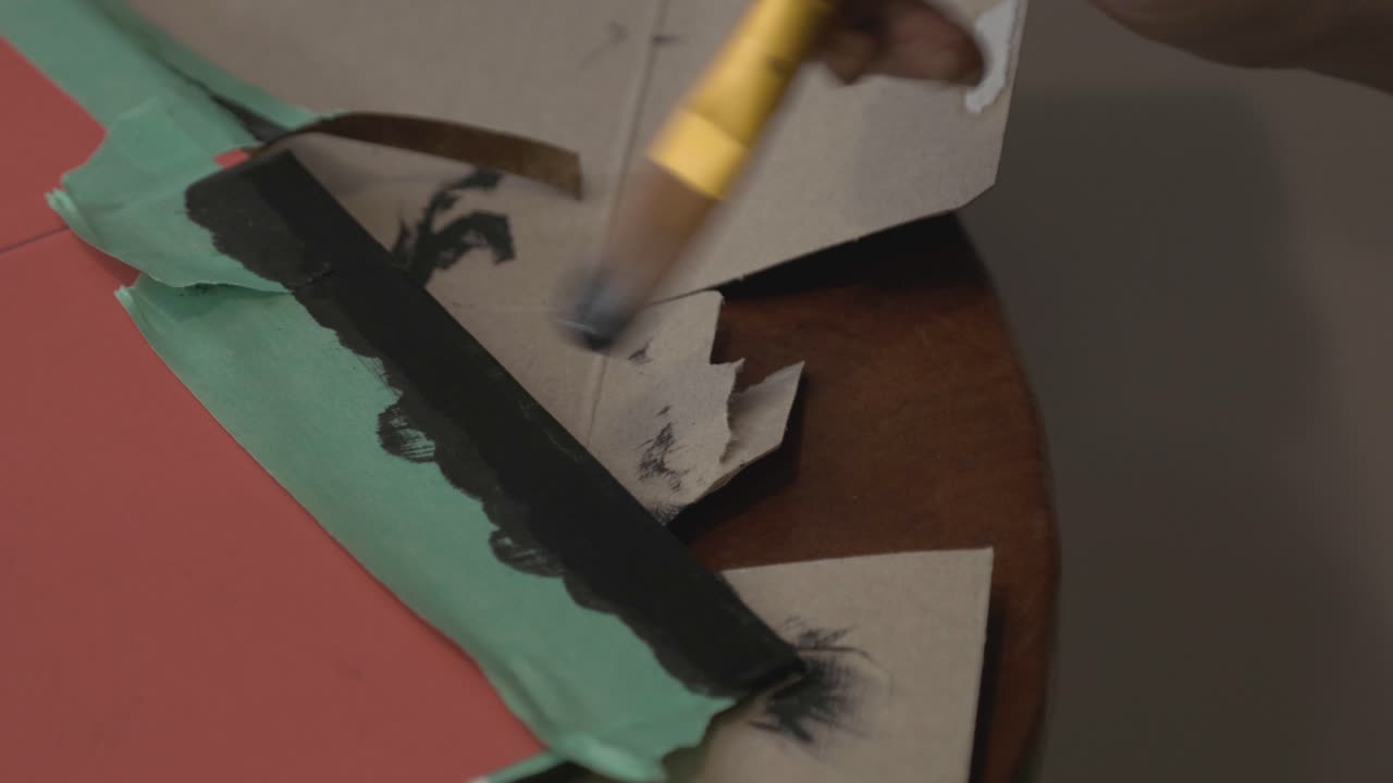 Man Applying Color Black Paint To The Border Of A Red Board - Close Up Shot
