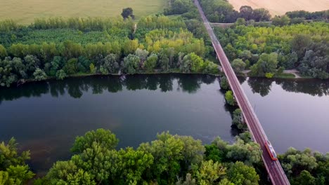 Train-travelling-on-railway-bridge-over-river-in-countryside,-Slovakia