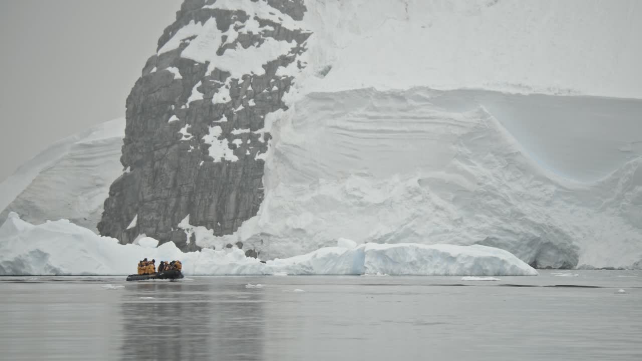 pequeño bote zodiac frente a un enorme glaciar y una costa montañosa