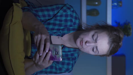 el video vertical de la mujer enviando mensajes de texto por teléfono por la noche es infeliz y triste.