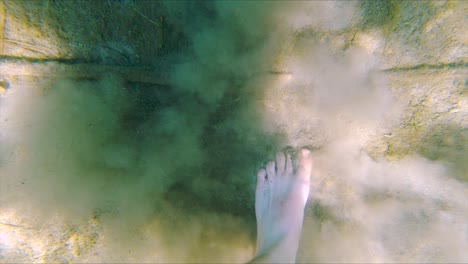 white male feet walk on sand bottom of lake in slow motion, wide underwater close up