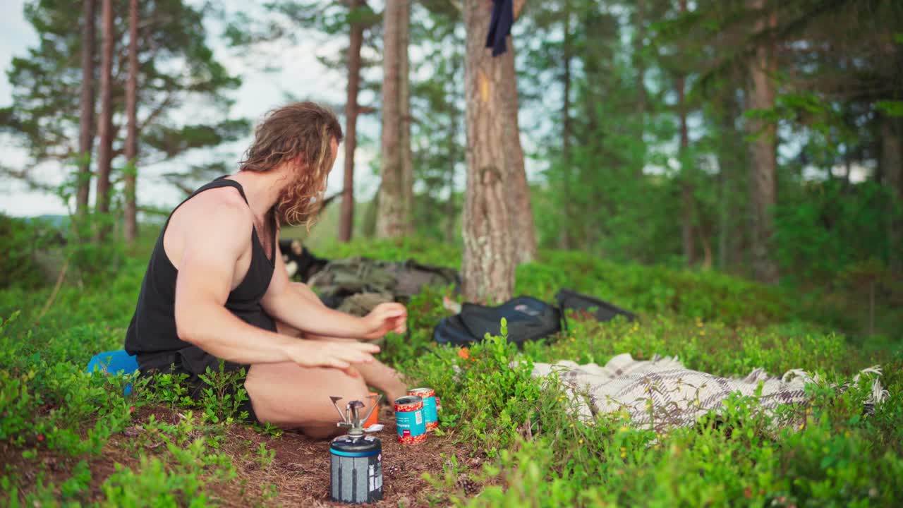 자연 속에서 휴대용 스토브를 사용하여 야외에서 요리하는 사람