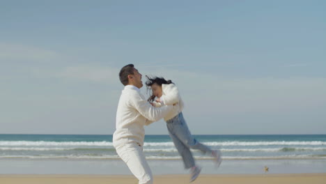 hombre japonés feliz levantando a su adorable hijita en la playa