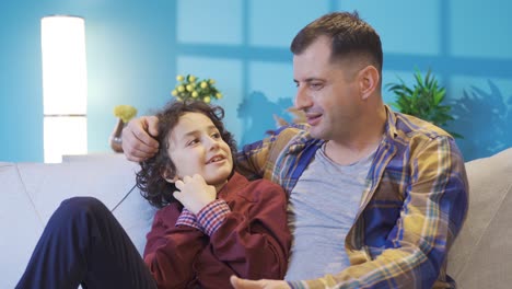 father and son sitting together on the sofa at home and chatting.