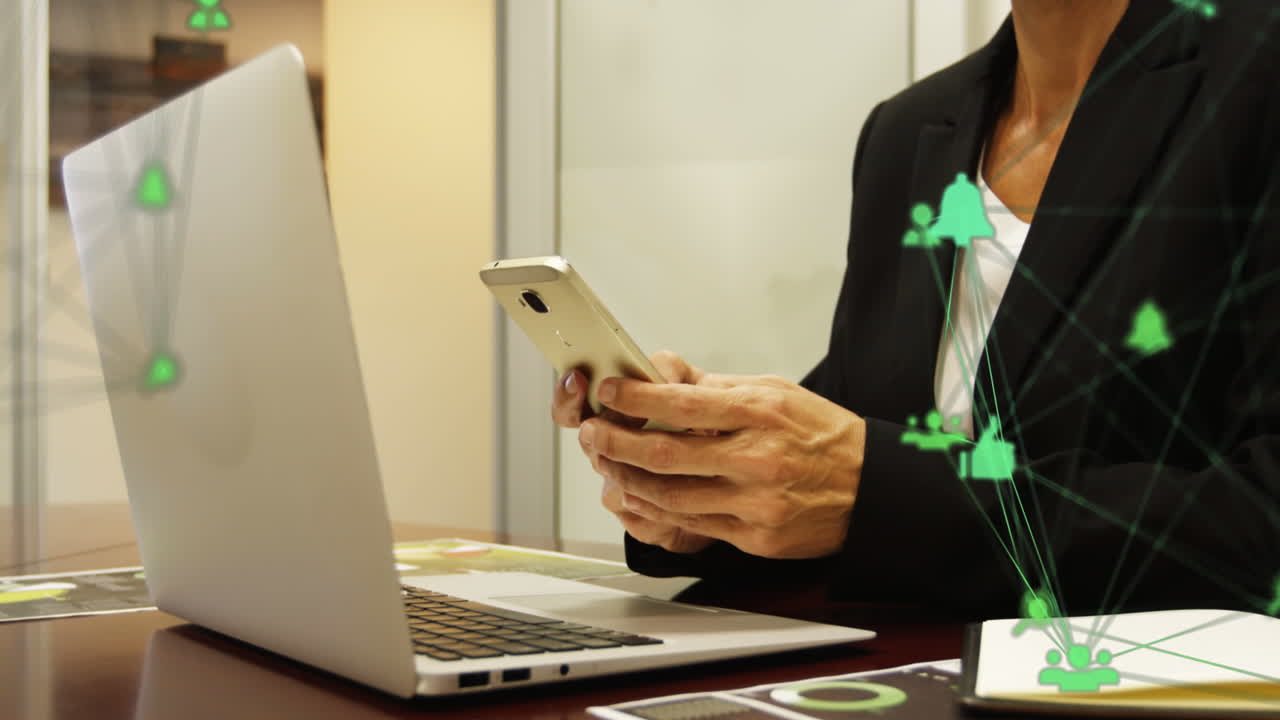 globo de iconos digitales girando contra la sección media de la mujer de negocios que usa un teléfono inteligente en la oficina