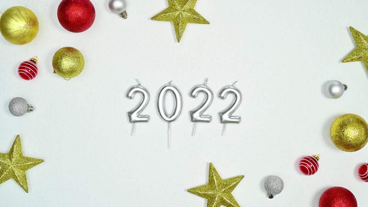 Christmas gold and red ornaments and stars move with 2022 year candles for New year on white theme. Stop motion