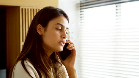 woman talking on mobile phone in living room 4k