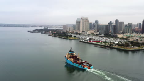 freighter navigating san diego bay near broadway pier with a view of the skyscrapers in san diego, california