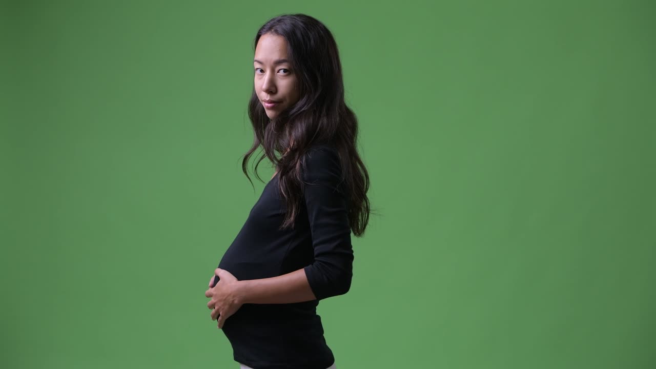 카메라를 바라보는 젊은 임신한 다민족 여성의 프로필 뷰