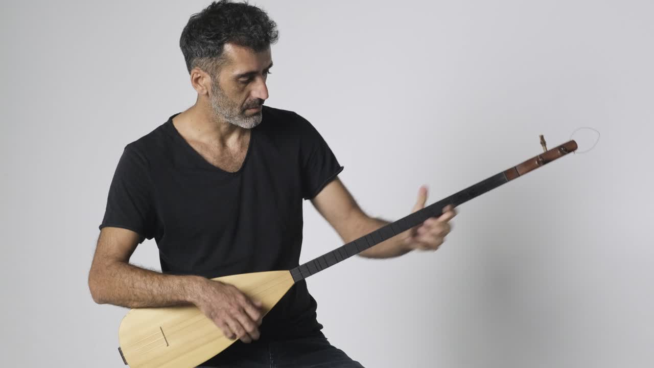 hombre del medio oriente tocando kopuz que es un instrumento de cuerdas llamado baglama con tres cuerdas en un fondo blanco.