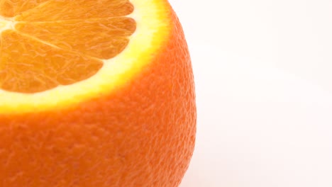 half frame cutted orange rotating on turn table. isolated on white. close up macro.