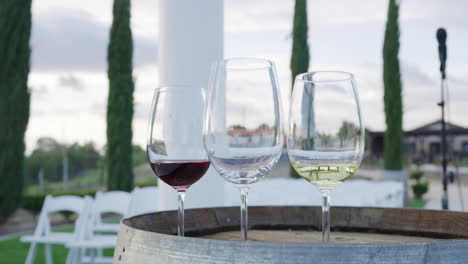 three glasses of water, white and red wine on a barrel in the garden of a vineyard during an event