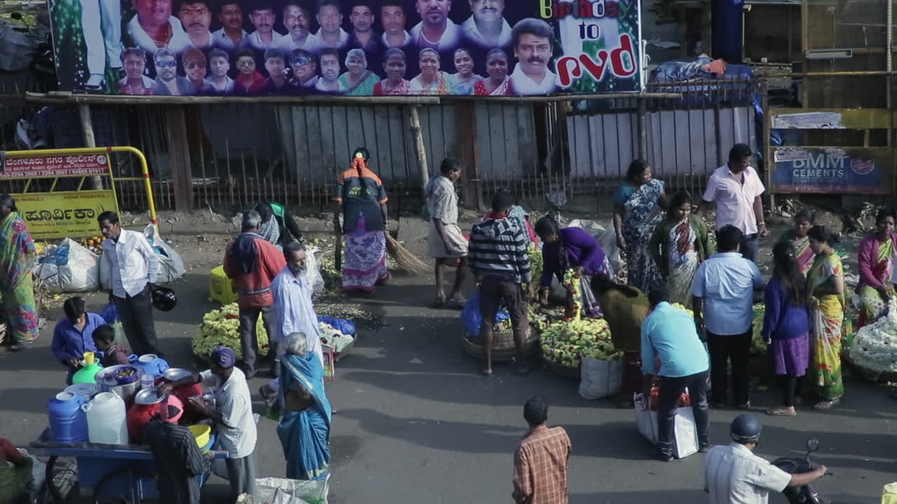 Bustling outdoor market scene in KR Market Bangalore India with people selling and buying flowers