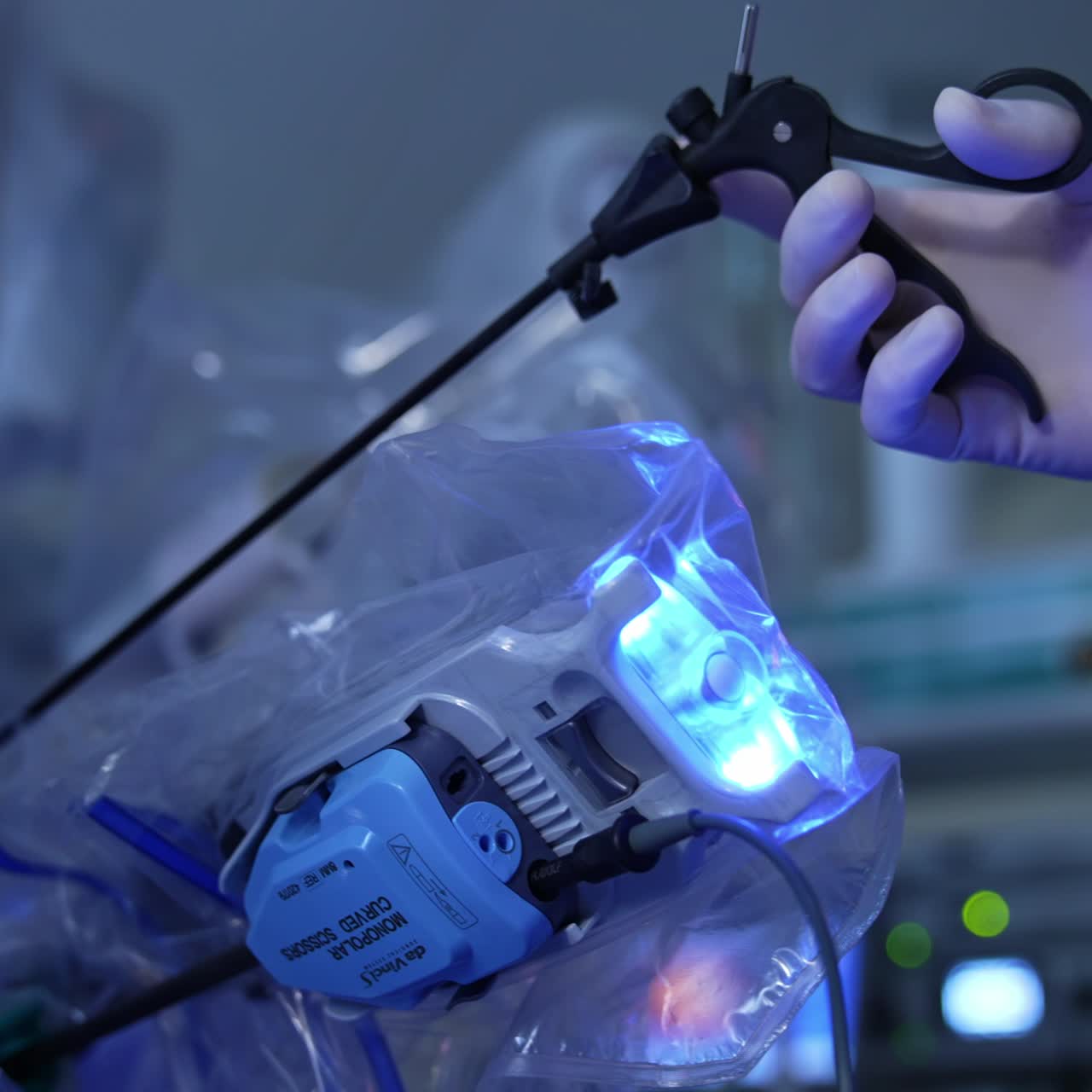 Gloved doctor's hand holds a long black instrument near the moving robotic arm. Laparoscopic surgery using Da Vinci robot at modern clinics