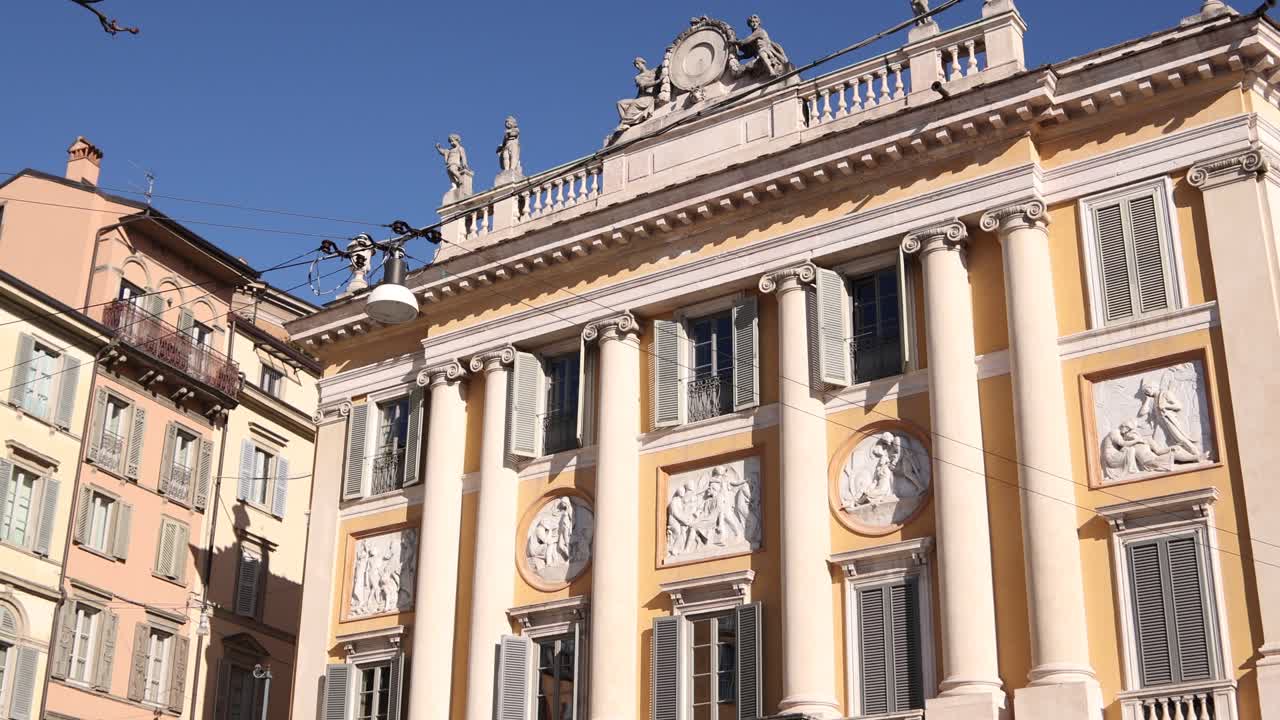 Vista esterna di un grande edificio neoclassico a Bergamo, Italia, caratterizzato da eleganti colonne e una facciata in pietra dettagliata alla luce del giorno.