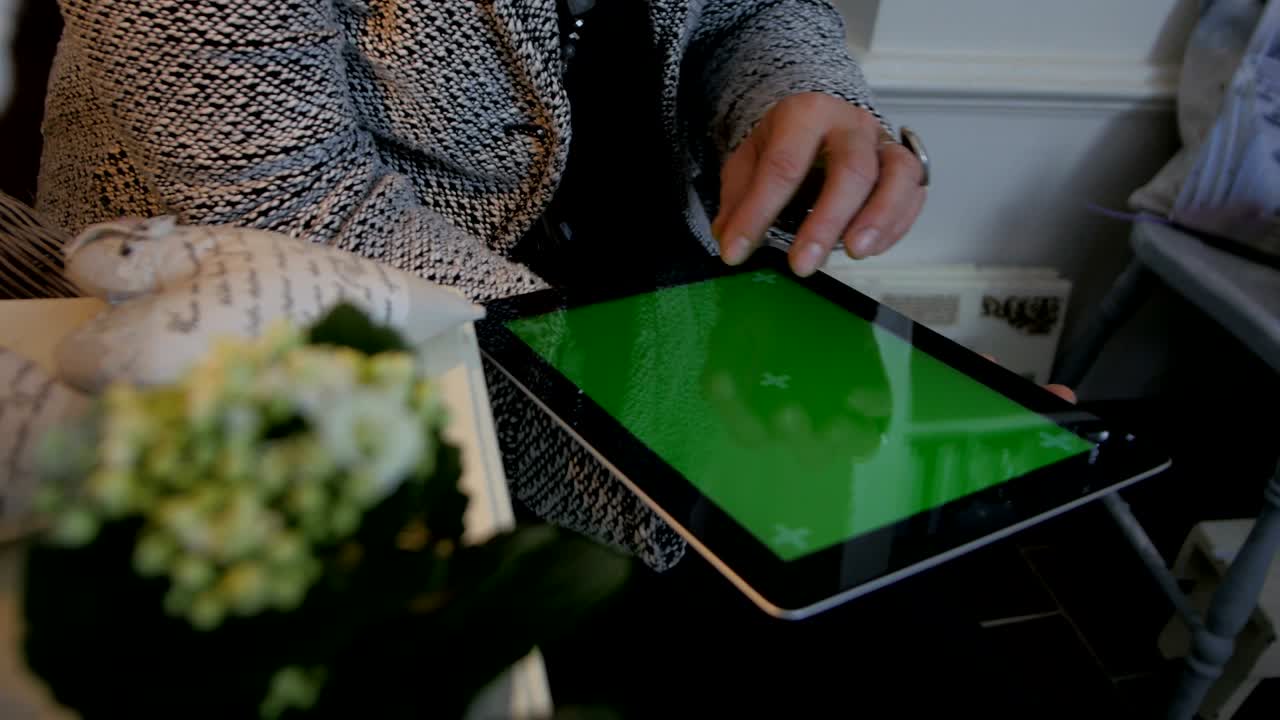 mujer sentada en el suelo y usando una tableta vertical con pantalla verde. fotografía de cerca de las manos de la mujer con un pad. concepto de tecnología e internet