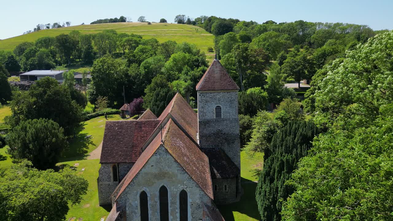 una toma de st lawrence, la iglesia del mártir en godmersham, con campos verdes brillantes y árboles circundantes