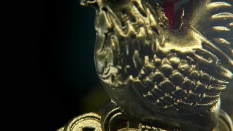 chinese new year traditional golden chicken zodiac statue, hanging gold rooster sitting on money coins asian symbol, glowing background with blurry depth of field, cinematic macro tilt up 4k