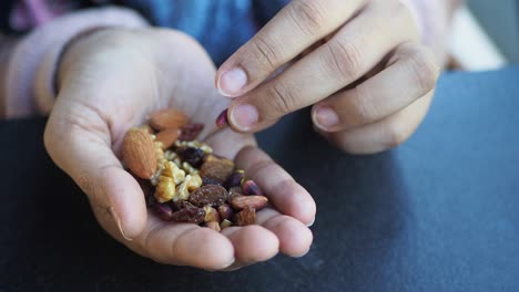 Hand holding a mix of nuts and raisins